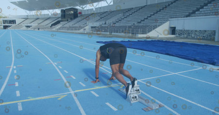 Bending male sprinter pushing off starting blocks on blue track next to protective mat, copy space....