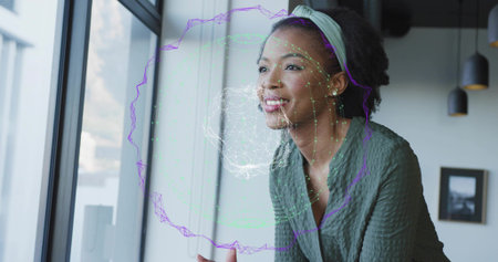 Leaning woman wearing green top holding coffee mug in office, with holographic wireframe projection....