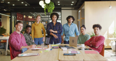 Collaborating seven professionals in formal attire at open-plan office with laptops and coffee cups. Teamwork, collaboration, diversity, modernoffice, productivity, brainstorming, corporateの写真素材