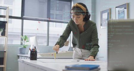 Designer drawing on blueprint with metal compass at design studio, including scale model. Creative, professional, minimalist, innovative, drafting, workspace, interiorの写真素材