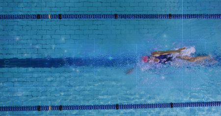 Swimming woman performing front crawl in lap pool, with lane dividers, stripe, pink cap and goggles....