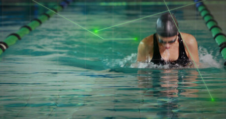 Breaststroking swimmer in lane flanked by green-black dividers wearing black swimsuit, copy space. Athlete, aquatic, fitness, minimalist, training, wellness, sportの写真素材