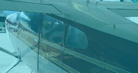 Showing small aircraft fuselage on airport ramp, with cabin windows and wing support struts....