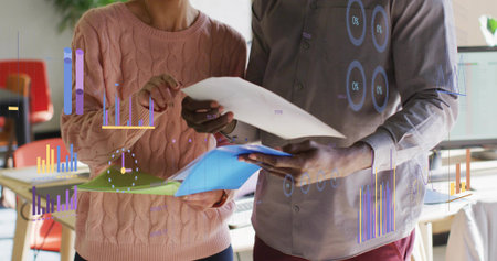 Professionals reviewing reports and color coded folders in office, with floating charts. Business, productivity, data, analytics, teamwork, collaboration, modernの写真素材