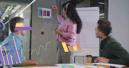 Presenting data woman presenter using marker on glass wall in modern meeting room, with flipchart....