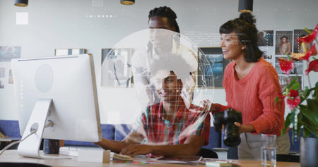 Collaborating colleagues examining data on desktop monitor with digital globe overlay in office. Creative, teamwork, innovation, modern, productivity, design, technologyの写真素材