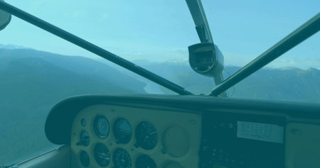 Cockpit panel showing analog gauges in flight framing mountain lake, with radio stack and camera....