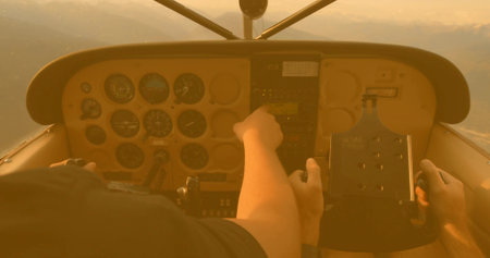 Pilot and co-pilot adjusting panel controls during sunset flight, with radio stack and yoke....