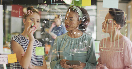 Four colleagues collaborating in office, with glass board sketches, sticky notes and tablet device. Collaboration, teamwork, innovation, brainstorming, modernoffice, creativeprocess, groupdiscussionの写真素材