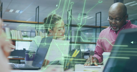 Collaborating woman and man reviewing paperwork and laptops in office, circuit overlay, copy space. Professional, teamwork, innovation, modern, digital, communication, productivityの写真素材