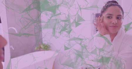 Applying face cream Indian woman wearing white bathrobe at bathroom vanity mirror, copy space. Skincare, wellness, beauty, interior, minimalism, self-care, tranquilityの写真素材