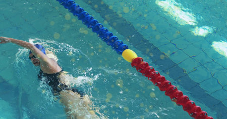 Swimming athlete wearing swimsuit performing crawl in pool lane with divider floats, copy space....