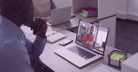 Mature worker watching remote presenter on open laptop at desk with notebook smartphone, copy space. Professional, teamwork, collaboration, digital, modern, communication, productivityの写真素材