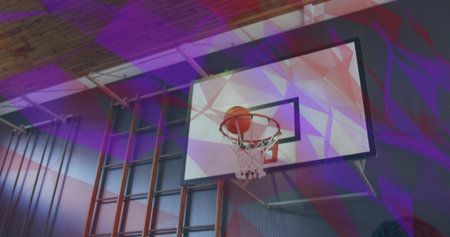 Dropping orange basketball through white net on backboard and rim at gym. Sport, fitness, activity, athletic, training, dynamic, exerciseの写真素材