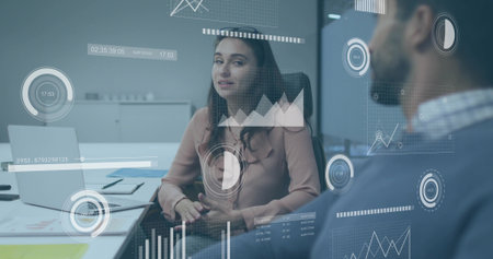 Businesswoman wearing blouse discussing data in meeting room, with laptop and data visualizations. Corporate, teamwork, analytics, professional, modern, collaboration, presentationの写真素材