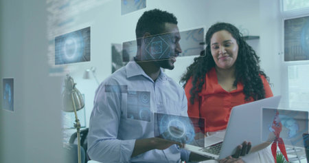 Two colleagues in button-up shirts collaborating in office, reviewing laptop with digital overlays. Technology, teamwork, innovation, modern, communication, productivity, dataの写真素材