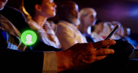 Holding smartphone with suit-sleeved hand under lighting at conference with avatar icon, copy space. Technology, networking, professional, communication, digital, corporate, modernの写真素材