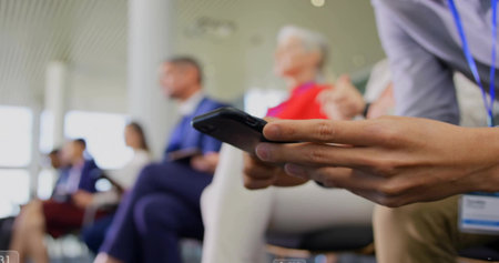 Showing businesswoman holding black smartphone at chest height in conference room, copy space. Professional, technology, networking, teamwork, modern, communicationの写真素材