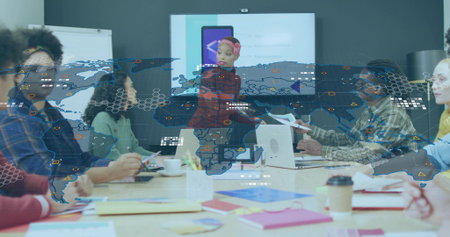 Presenting Hispanic woman gesturing toward display screen in meeting room, with documents, laptops. Collaboration, professionalism, teamwork, corporate, innovation, communication, modernの写真素材