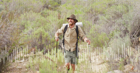 Walking bearded hiker using trekking poles along narrow dirt trail in hiking boots, with backpack. Adventure, exploration, wilderness, rugged, trail, outdoor, enduranceの写真素材