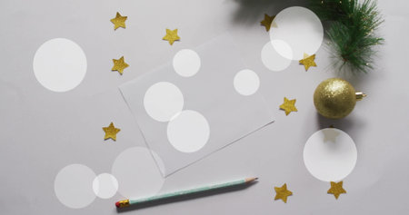 Image of white spots over blank card with christmas decorations on white background. Christmas, tradition and celebration concept digitally generated image.の写真素材
