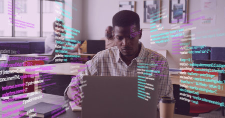 Mature developer in plaid shirt typing code on laptop in office, with coffee cup and notebooks. Collaboration, teamwork, innovation, technology, modern, productivity, officeの写真素材