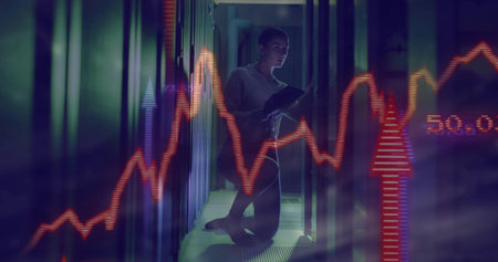 Kneeling technician examining server racks in data center, with tablet and floating stock graphs....
