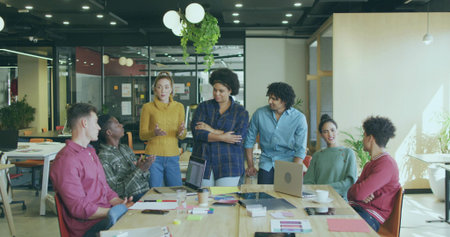 Seven office professionals collaborating around conference table in office, with laptops. Collaboration, teamwork, modernoffice, brainstorming, communication, professional, businessmeetingの写真素材
