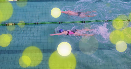 Two swimmers wearing briefs and swimsuit performing freestyle in pool, lane dividers, goggles, cap....