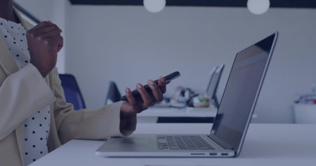 Contemplating businesswoman in blazer holding smartphone at office desk with laptop, copy space. Professional, workspace, modern, corporate, communication, productivity, minimalistの写真素材
