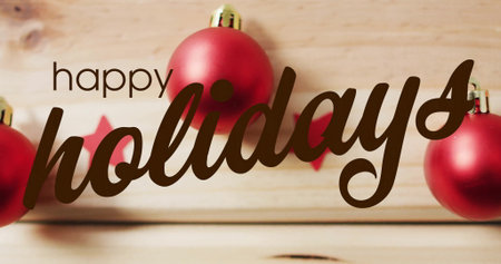 Image of happy holidays text and christmas baubles on wooden background. Christmas, celebration and digital interface concept digitally generated image.の写真素材
