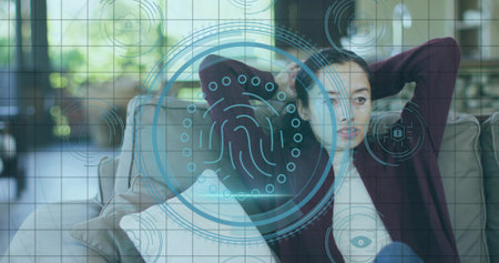 Reclining woman wearing maroon cardigan at home on sofa by windows with holographic interface. Futuristic, biometric, security, relaxation, modern, cozy, technologyの写真素材