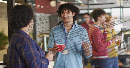 Gesturing curly-haired man holding red mug presenting ideas in open office, with glass board notes....
