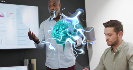Gesturing man in button-up shirt presenting 3D brain hologram in meeting room, with display screen....