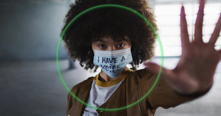 Raising hand woman signaling stop in concrete tunnel, with slogan mask and neon-green light overlay. Urban, empowerment, activism, contrast, modern, resilience, street styleの写真素材