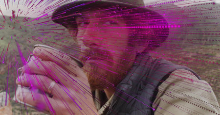 Outdoorsman in bucket hat quilted vest sipping metal cup in shrubland, with magenta-purple streaks....