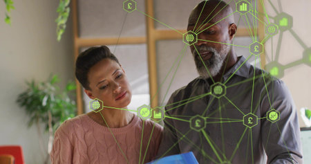Examining woman in pink sweater and bearded man reviewing blue folder in office, with network icons. Collaboration, teamwork, innovation, data, analytics, professionalism, modernの写真素材
