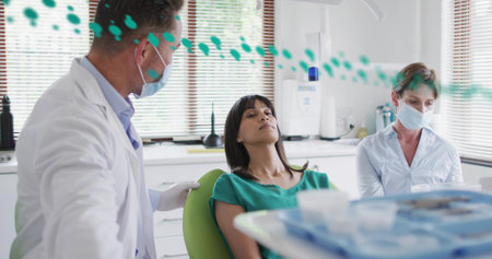 Examining dentist placing hand on patient shoulder in dental clinic, with chair and instrument tray. Dental, healthcare, clinic, professional, examination, medical, patient careの写真素材