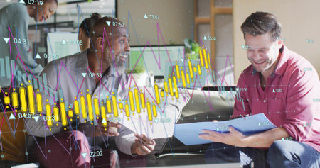 Team collaborating at desk in office, reviewing laptop, monitors, blue folder and graph overlays....