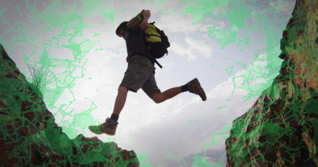 Leaping man in wide-brimmed hat, hiking boots and backpack across rugged rock gap in desert canyon. Adventure, exploration, wilderness, outdoor, rugged, daring, athleticの写真素材