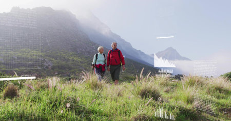 Trekking senior couple wearing layered jackets and boots, exploring alpine meadow with daypacks. Adventure, exploration, wilderness, outdoor, scenic, tranquility, natureの写真素材