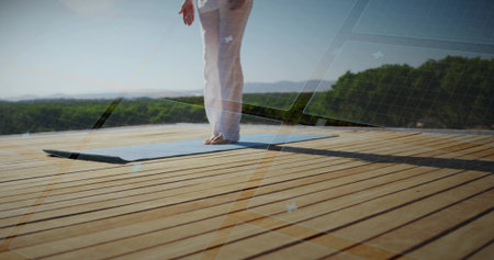 Balancing adult woman holding yoga pose on light blue mat on wooden deck, with grid overlays. Fitness, mindfulness, outdoor, serenity, wellness, nature, meditationの写真素材