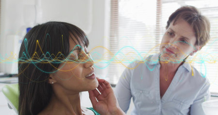 Touching chin patient seated in green chair consulting provider in exam room, with waveform overlay....