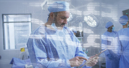 Mature surgeon reviewing digital data on tablet, operating under surgical lights in operating room. Medical, teamwork, innovation, healthcare, technology, precision, professionalismの写真素材