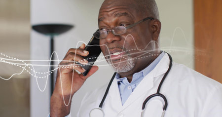 Talking doctor in white coat holding smartphone in clinic, showing stethoscope and digital waveform. Medical, healthcare, telemedicine, technology, professional, diagnostic, communicationの写真素材
