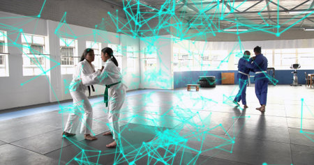 Judo practitioners training and grappling on dojo mats at training hall, with stationary bike....