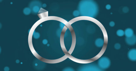 Glimmering diamond topped ring interlocking with plain silver band on teal background, bokeh lights. Elegance, luxury, celebration, romance, symbolism, abstract, graphicの写真素材