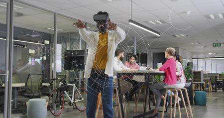 Gesturing man wearing VR headset interacting with virtual graphics in office space with bicycle....