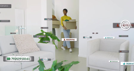 Walking mid-adult woman carrying box through modern living area, with digital overlay icons....