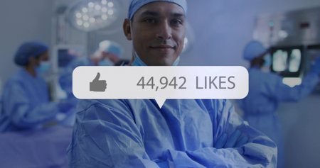 Standing male surgeon in blue scrubs and cap folding arms in operating room, with media overlay. Surgical team, hospital, clinical, healthcare, sterile, medical equipment, teamworkの写真素材